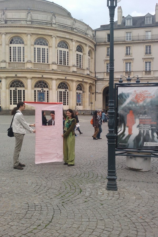 Photo de la place de la mairie, avec Trizek et Auregann tenant un grand papier au format des panneaux utilisés pour l'opération "10 ans de Wikipédia à Rennes".