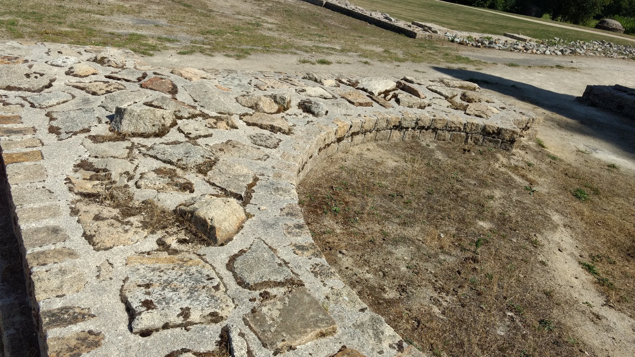 Photo d'une ruine romaine montrant un morceau de mur en arc de cercle