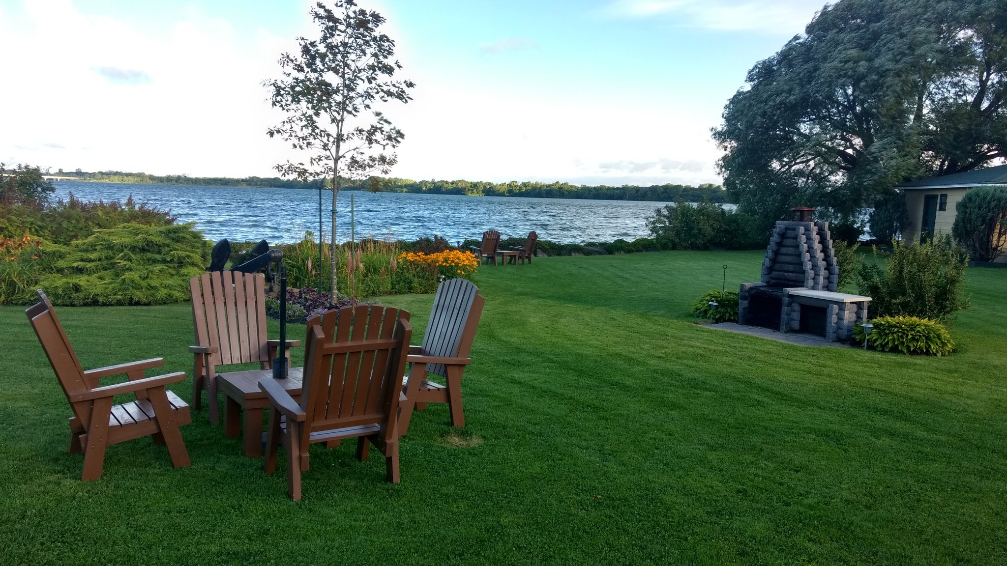 Vue charmante d'une pelouse au bord d'un lac, avec une table de jardin et un barbecue