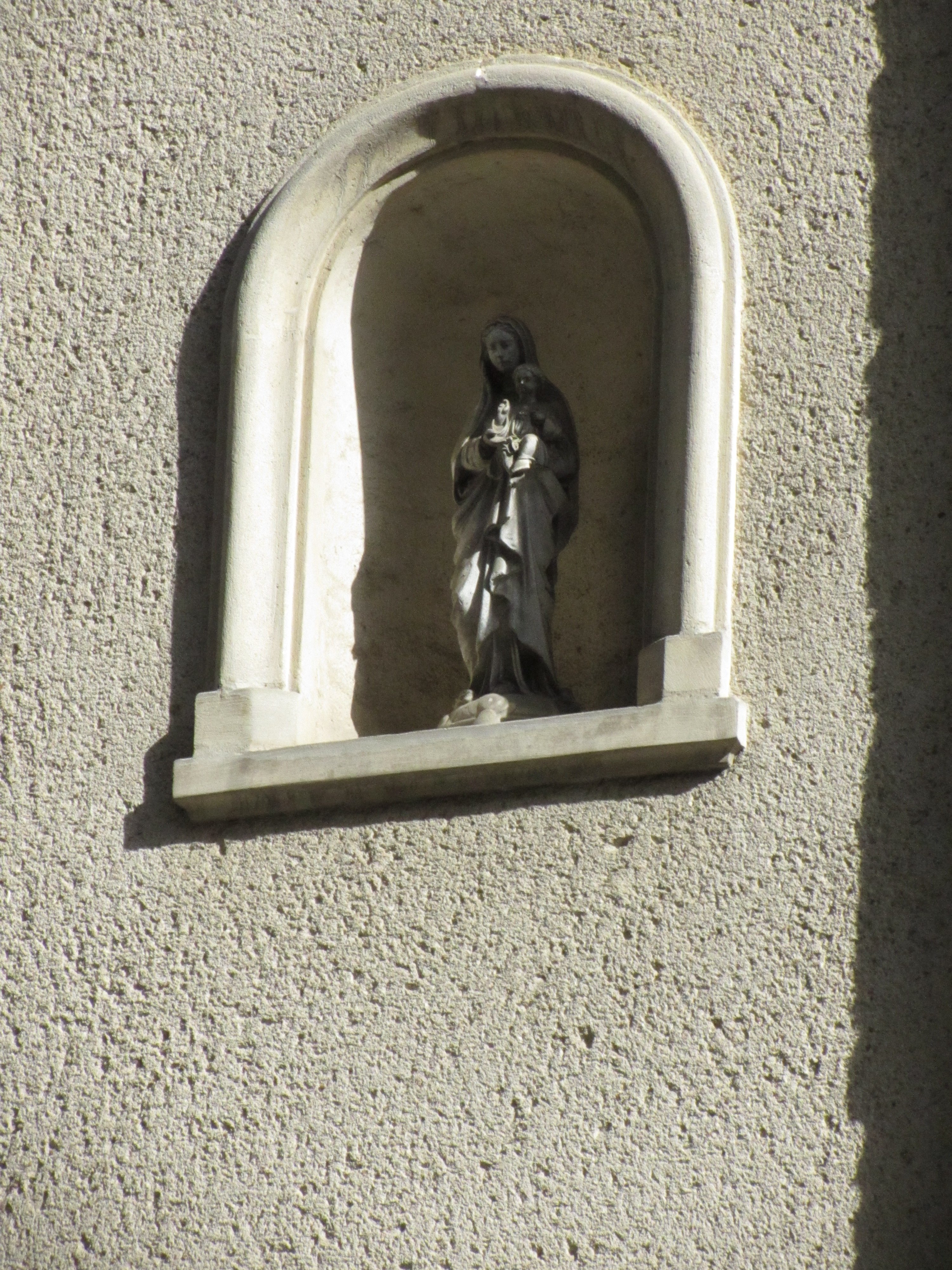 Une statuette de vierge à l'enfant dans une niche dans un mur