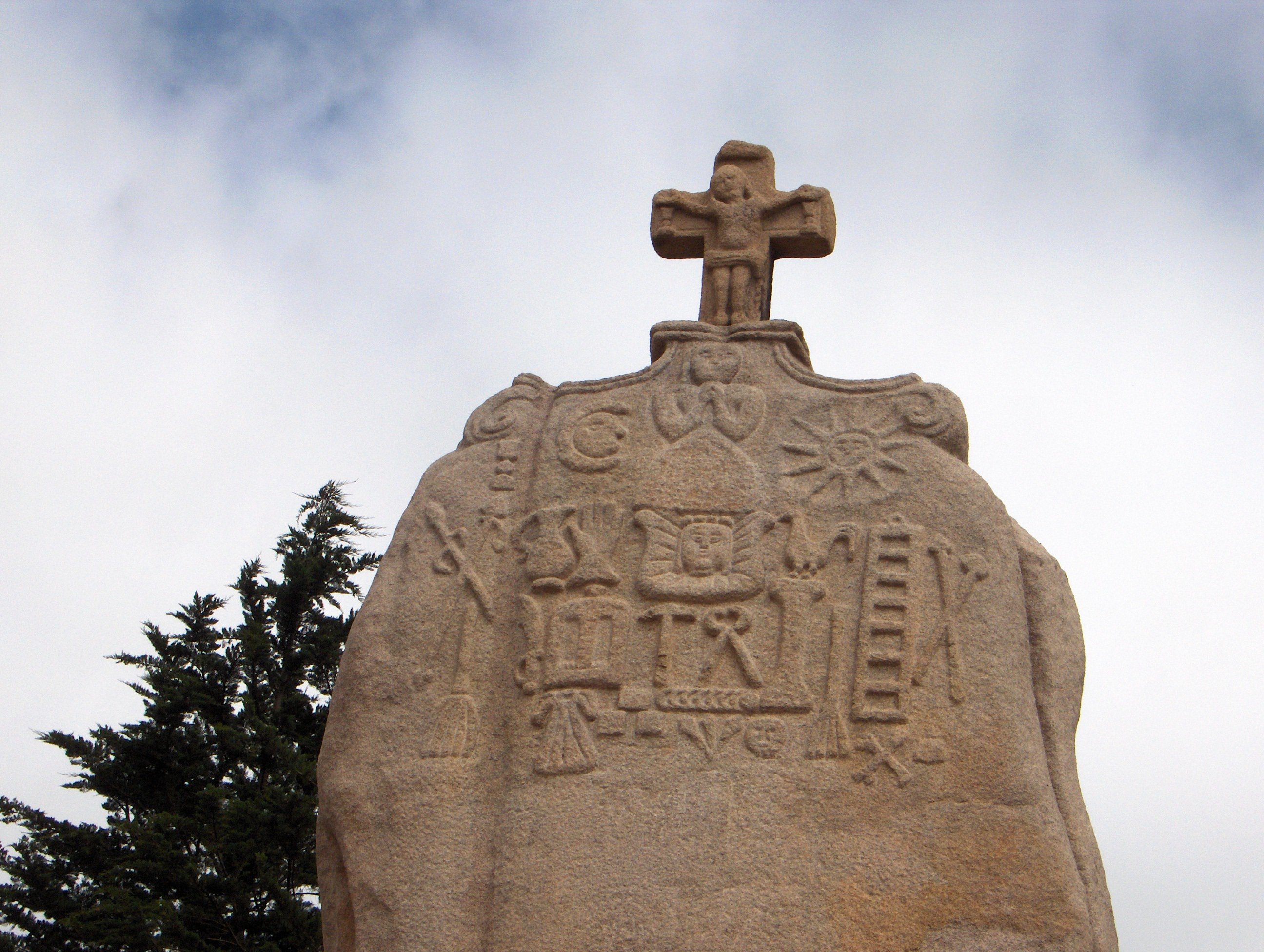 Le haut d'un menhir, qui a été surmonté d'un crucifix, et dont la surface est partiellement couverte de gravures.