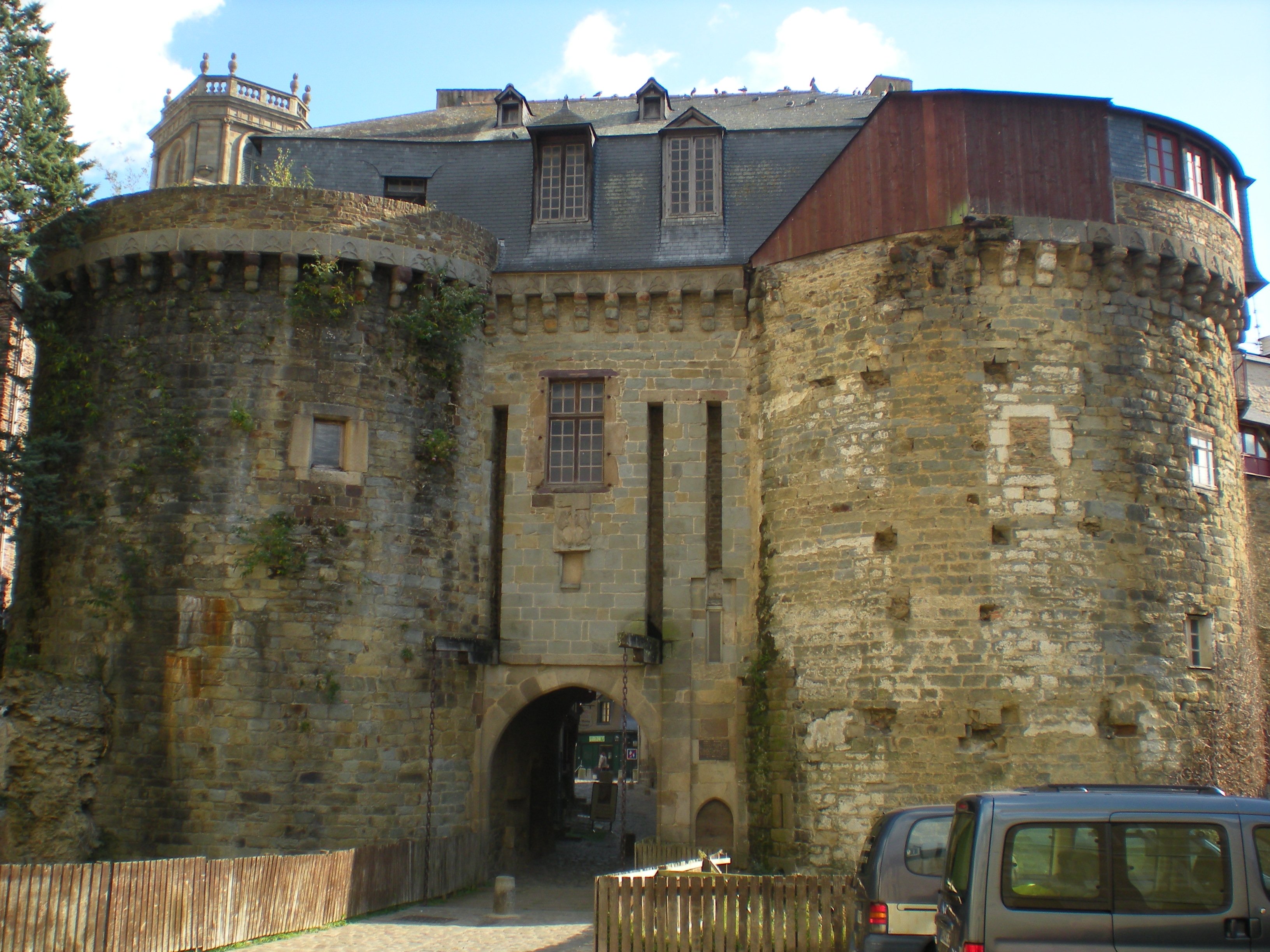 Une porte de ville médiévale, entourée par deux tours et surmontée par une maison d'habitation