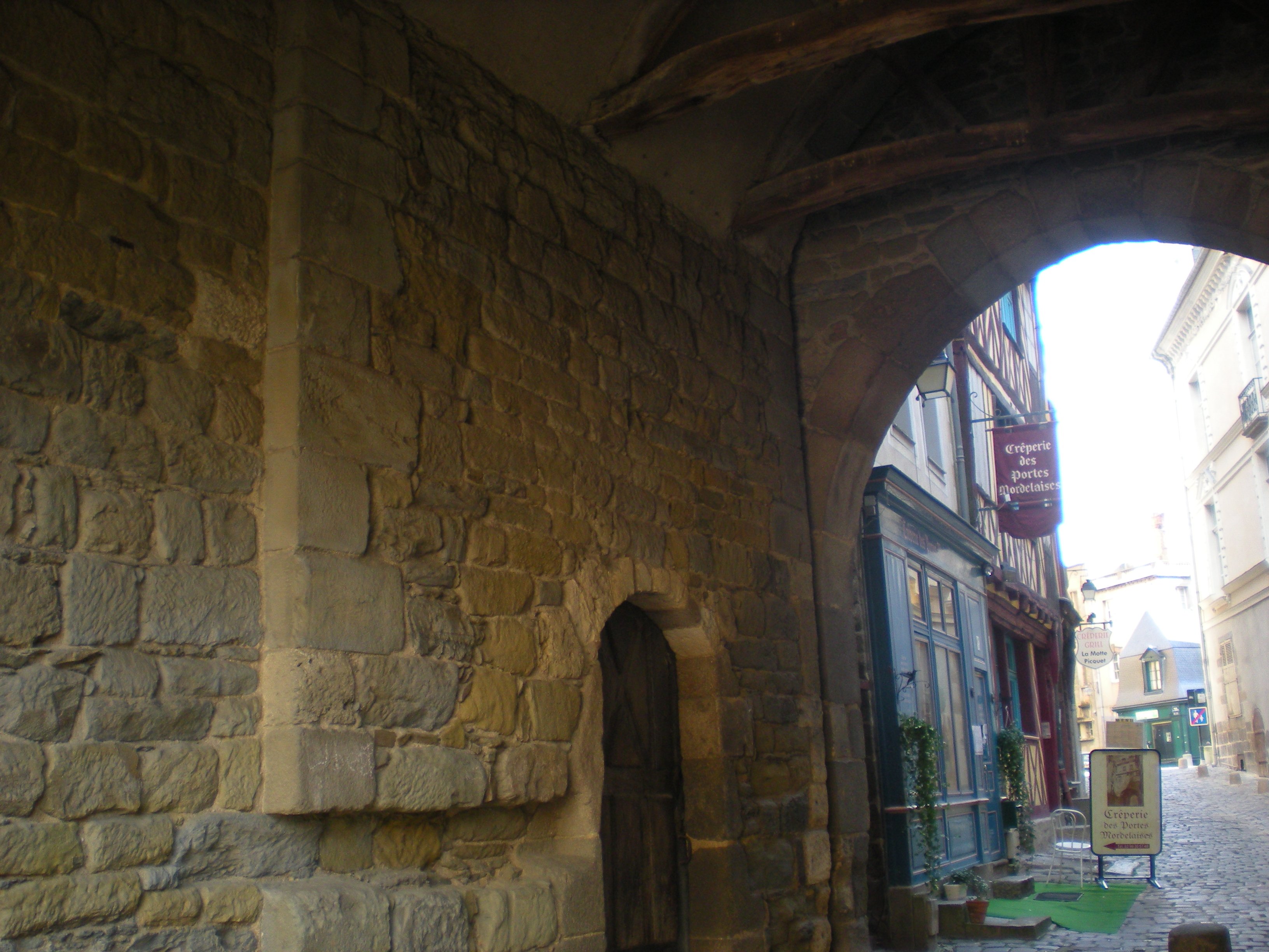 Mur en pierre à l'intérieur de la porte, le passage se prolongeant sur la rue Mordelaise avec ses façades à colombage.