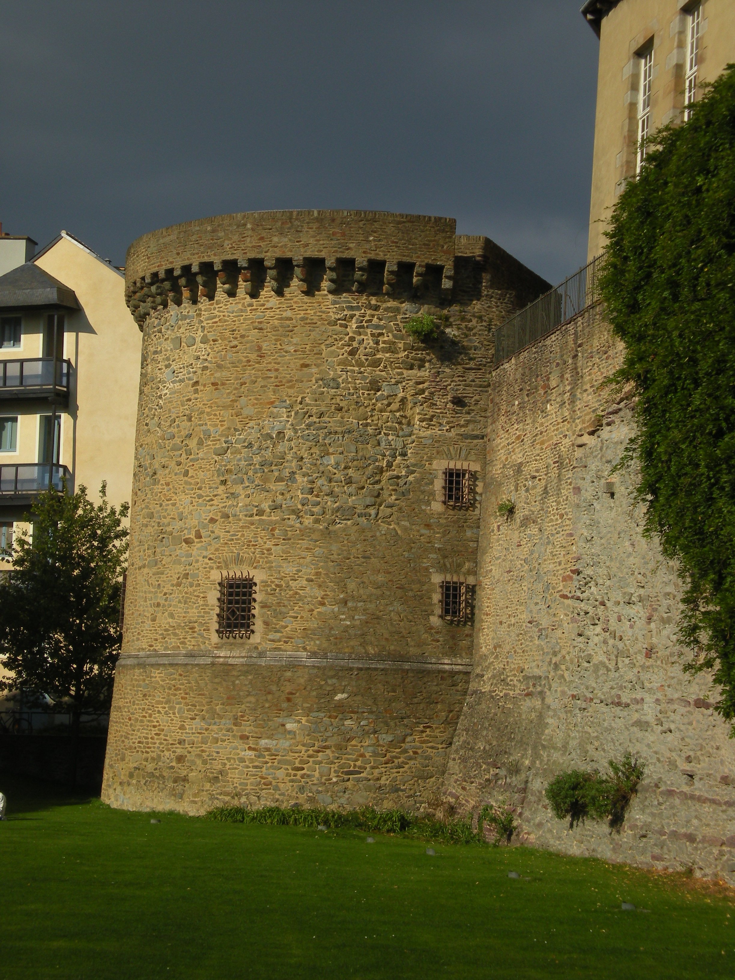Une tour médiévale le long d'un rempart, avec une pelouse devant