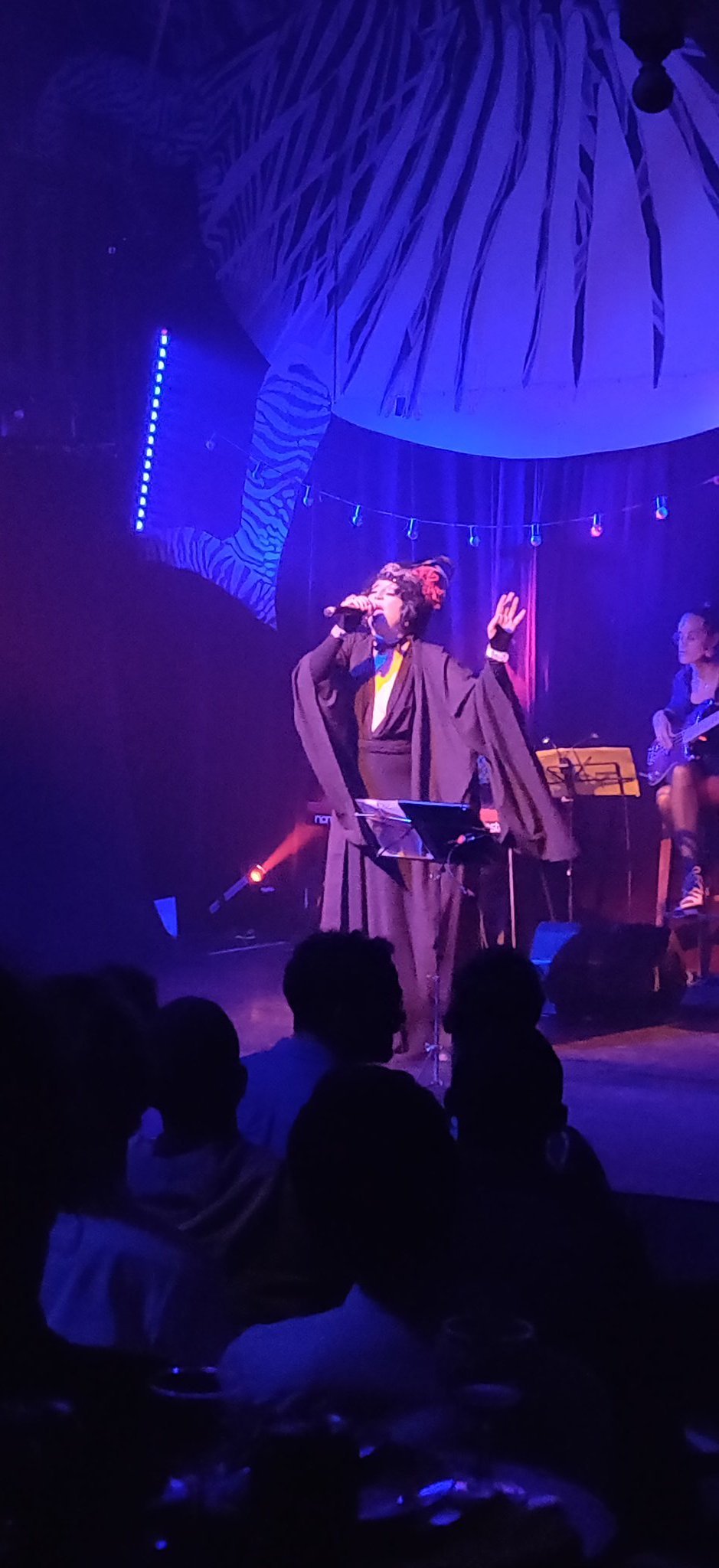 Une femme en kimono noir chante dans un micro