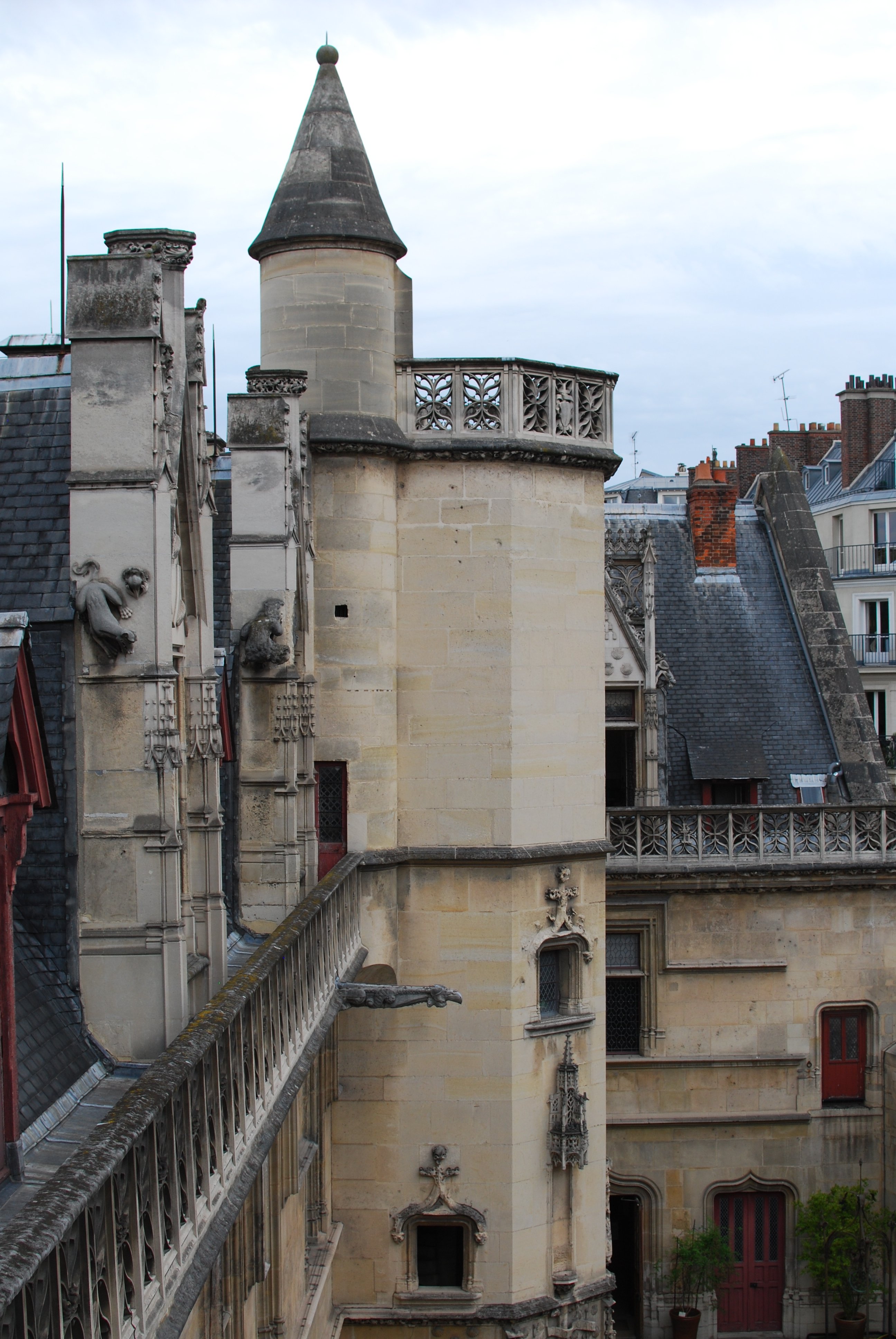 Le haut des murs de la façade de l'hôtel de Cluny, au niveau des toits. Trois encadrements de fenêtre dépassent, ainsi que la tour octogonale qui se finit par un toit-terrasse. Une petite tourelle attenante avec un toit pointu permet d’y accéder.